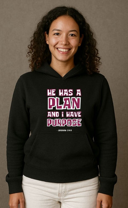 Smiling woman wearing black VerseWear by L'authority Christian hoodie with bold text 'He Has a Plan and I Have Purpose – Jeremiah 29:11' – inspirational faith-based streetwear.