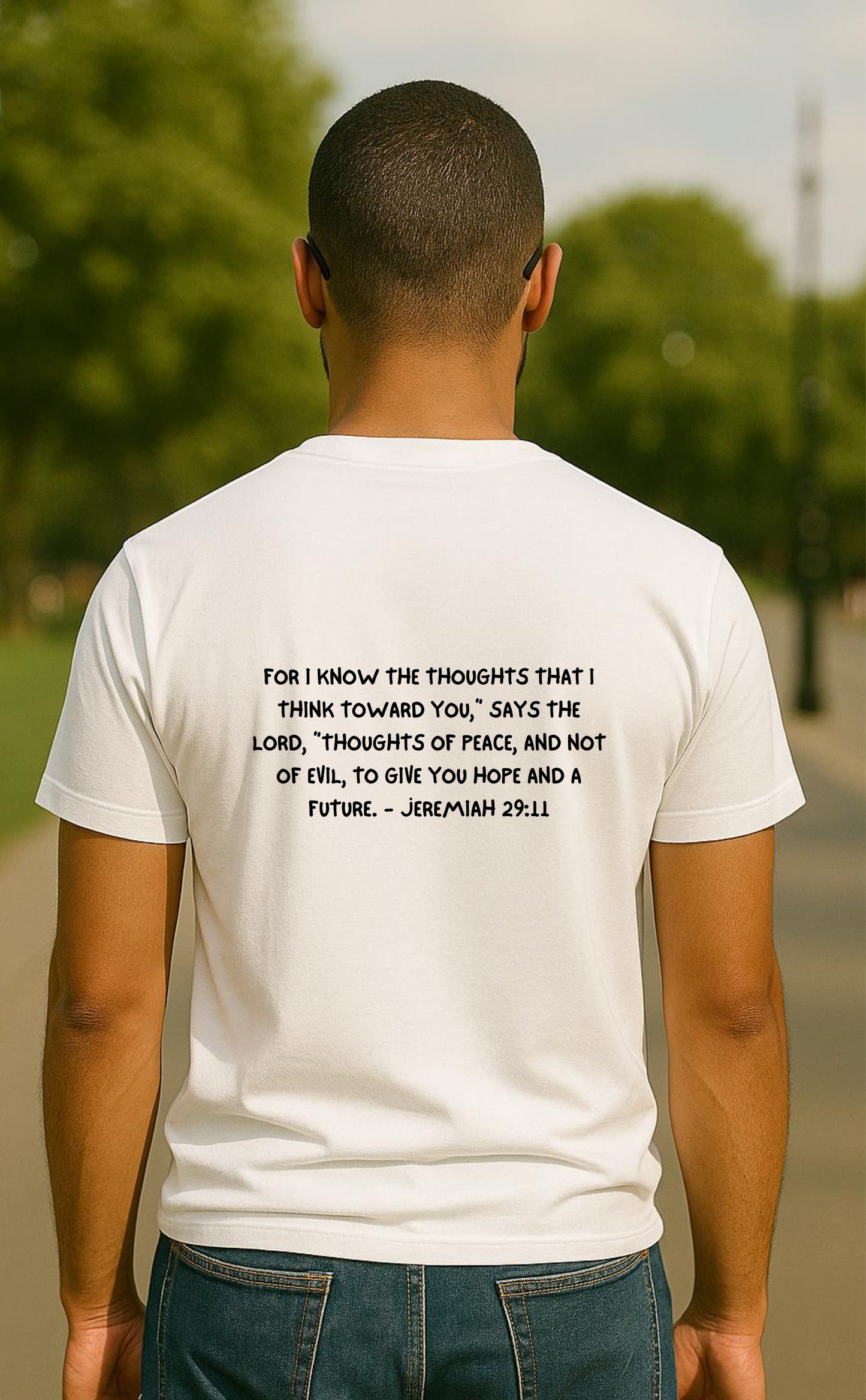 Back view of man wearing white t-shirt from VerseWear by L’authority featuring Jeremiah 29:11 – 'Haven’t I commanded you? Be strong and courageous. Don’t be afraid. Don’t be dismayed, for THE LORD your God is with you wherever you go.' – Christian streetwear in park setting