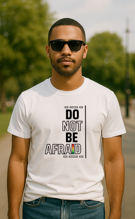 Man wearing white t-shirt from VerseWear by L’authority with bold vertical typography – 'Do Not Be Afraid' – featuring black text with red, yellow, and green accent in outdoor park setting